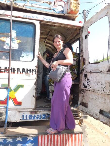 rédactrice web seo freelance en voyage debout à l'arriere d'un taxi brousse