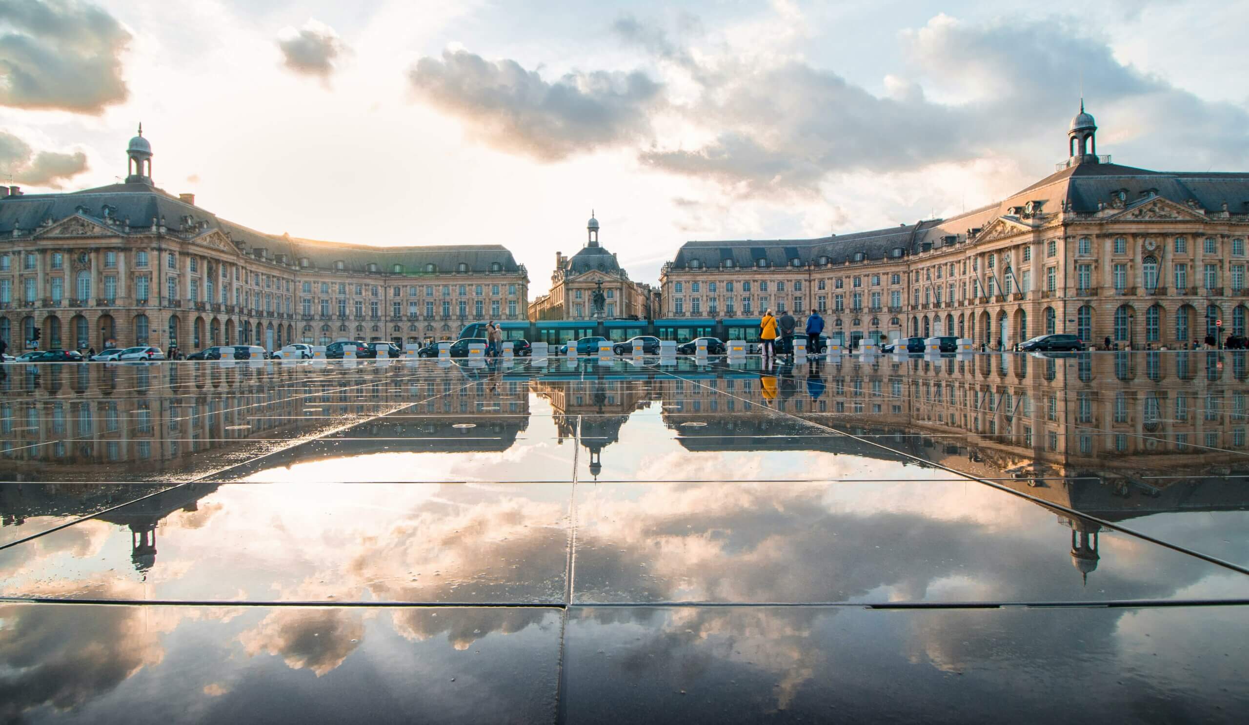 photo de la place de la bourse à Bordeaux prise depuis le miroir d'eau sur les quai de la Garonne